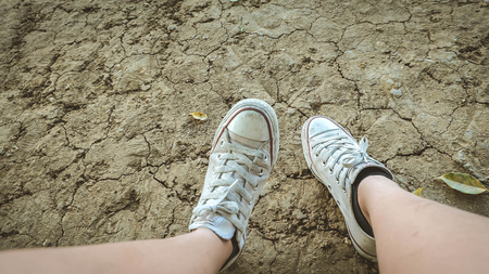 Male feet in gumshoes on green grass in the park at sunsetの写真素材