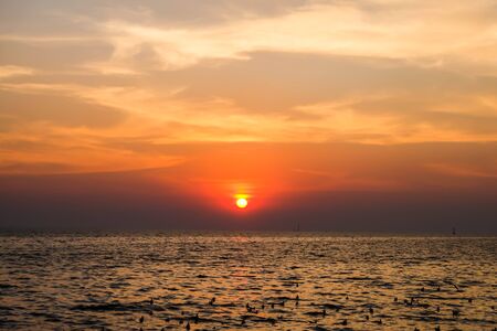 Beautiful blazing sunset landscape at black sea and orange sky above it with awesome sun golden reflection on calm waves as a background. Amazing summer sunset view on the beach. Russian nature, Sochiの写真素材