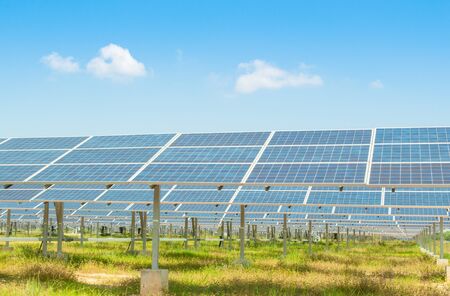 Solar panel with green grass in front of a blue sky with clouds
