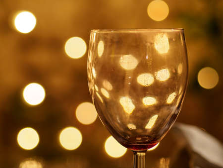 Closeup macro detail of an empty wine glass reflecting beautiful yellow lights in the background. Shallow Bokeh focus. London, England. Party and night life.の写真素材