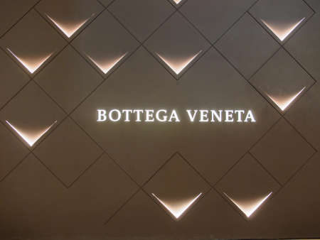 Wide view of the Bottega Venta logo and abstract lights pattern on the wall in front of a boutique store. Siam Paragon department store. Luxury and spending.のeditorial素材