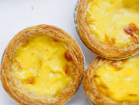 Closeup macro detail of multiple freshly baked egg tarts on a white background. Bangkok, Thailand....