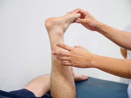 Closeup of a doctor examining a patient's left leg for fractures. Healthcare and orthopedic surgery.