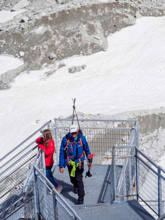 CHAMONIX, FRANCE - APRIL 26, 2018: Wide vertical view of a father and his daughter climbing the metal stairs leading to the entrance to Mer de Glace's glacier ice caves. Travel and tourism.のeditorial素材
