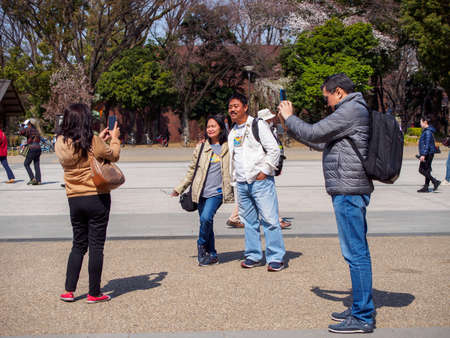 TOKYO, JAPAN - MARCH 27, 2019: Vietnamese tourists, couples, pose for smartphone photos and selfies...