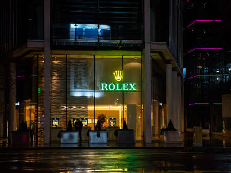 LONDON, UNITED KINGDOM - MARCH 7, 2019: Wide angle view of a Rolex AD with a glowing logo through the storefront windows at Knightsbridge. Luxury Swiss watch industry.のeditorial素材