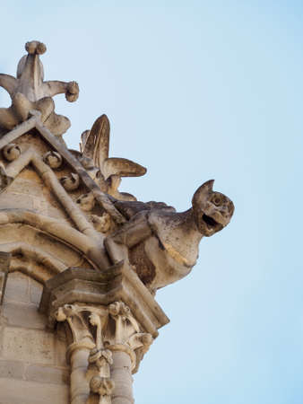 PARIS, FRANCE - MAY 7, 2018: Closeup vertical detail of a gargoyle limestone statue on the rooftop...
