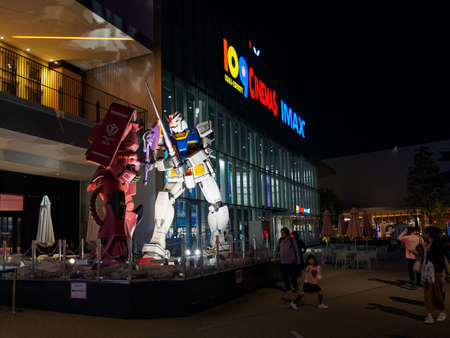 OSAKA, JAPAN - APRIL 3, 2018: Wide angle of the Gundam and Zaku life-sized mecha replicas posed and illuminated in front of EXPOCITY, Suita, at night. Travel and Anime tourism.のeditorial素材