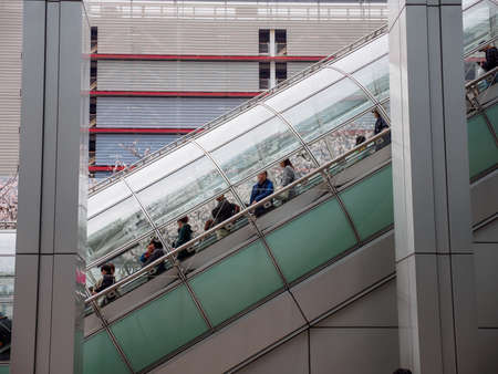 TOKYO, JAPAN - MARCH 30, 2019: Tourists ride a tubular escalator down to the malls at the Fuji...