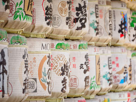 NAGOYA, JAPAN - MARCH 28, 2018: Close-up of empty sake barrels with colorful logos stacked on top of each other as a Shinto offering, known as Kazaridaru. Atsuta Shrine. Travel and religion.のeditorial素材