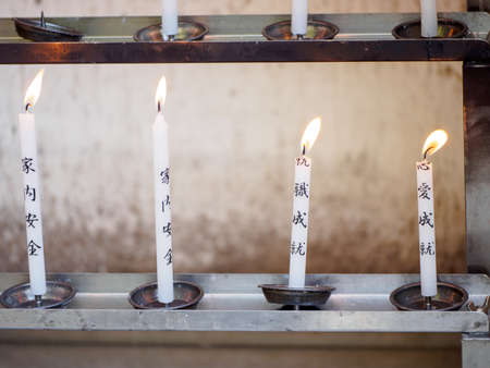 KYOTO, JAPAN - APRIL 2, 2018: Closeup detail of multiple prayer candles with lucky spells glowing on steel holder racks. Kinkaku-ji golden pavilion. Travel and religion.のeditorial素材