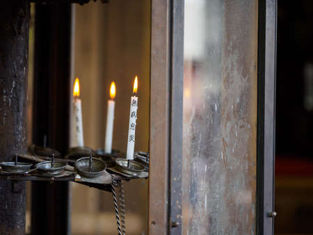 KYOTO, JAPAN - APRIL 2, 2018: Closeup of multiple lit Buddhist prayer candles in a candle box....