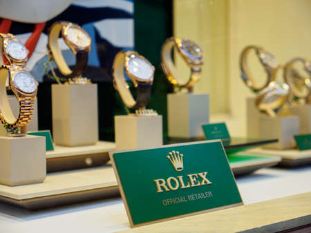 BATH, UNITED KINGDOM - MARCH 5, 2019: Wide close-up of a Rolex plaque on display next to multiple gold Datejust, Cellini, and other watches at a boutique. Luxury Swiss timepiece industry.のeditorial素材