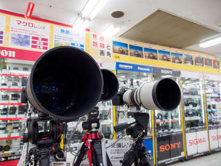 OSAKA, JAPAN - APRIL 3, 2018: Wide closeup of multiple DSLR cameras with large telephoto lens and tripods on sale at a Bic Camera. Dotonbori, Namba. Travel and electronics business.のeditorial素材