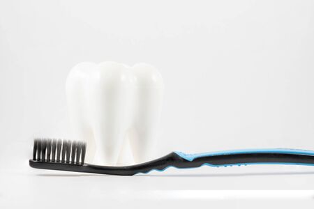 White model tooth with black tooth brush isolated on white background
