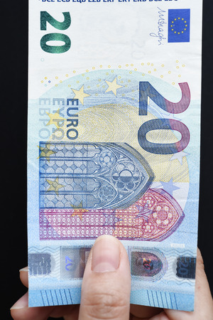 20 Euro on hand and gold coins on black backgroundの写真素材