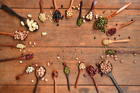 Assortment of beans and lentils in wooden spoon on teak wood backgroundの写真素材