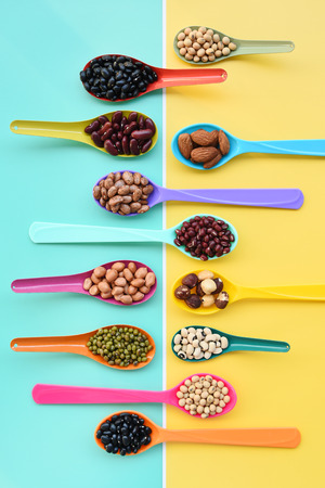 Assortment of beans and lentils in wooden spoon on teak wood backgroundの写真素材