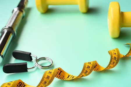 Fitness concept dumbbell and measuring tape for background
