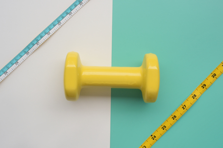 Fitness concept dumbbell and measuring tape for background