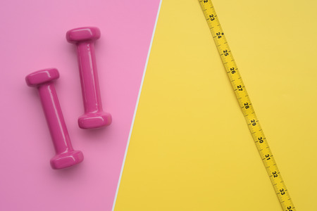 Fitness concept dumbbell and measuring tape for background