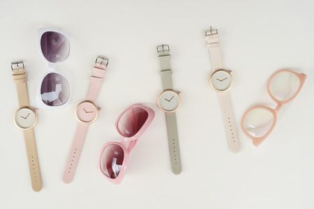 Set of multicolored wristwatches with fashionable sunglasses for background