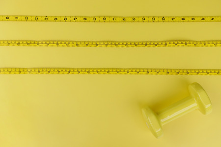 Fitness concept dumbbell and measuring tape for background