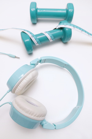 close up of headphones with dumbbell and measuring tape isolated on white backgroundの写真素材