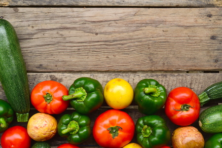 Cucumbers, tomatoes and sweet pepper on wooden table for backgroundの写真素材