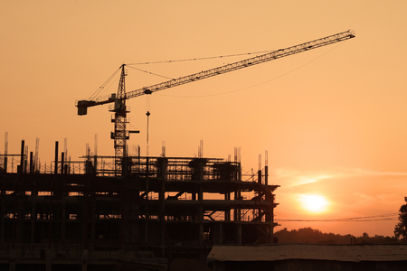 Silhouette building crane and buildings under construction against evening sky.の写真素材