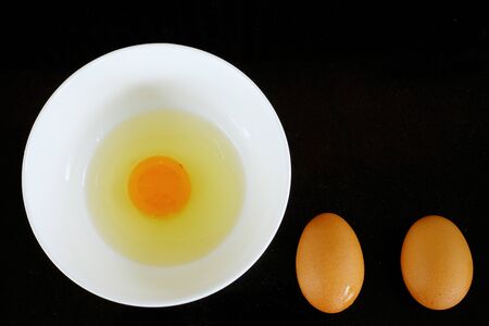 Top view of eggs in bowl on black background