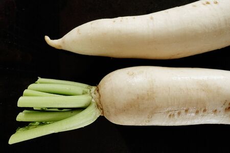close up of fresh white radish on black background