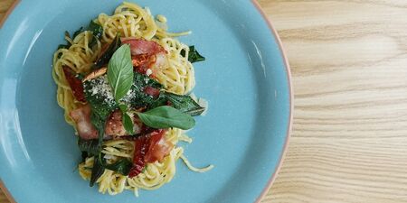 Spaghetti spicy with bacon and basil dried chilli in the blue dish on backgroundの写真素材