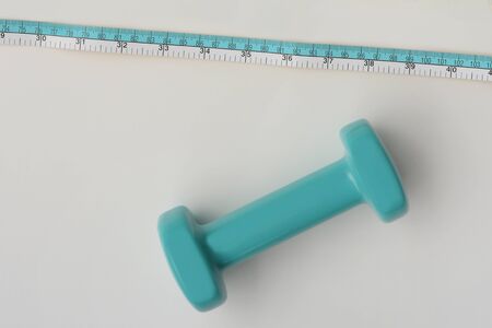Fitness concept dumbbell and measuring tape isolated on white backgroundの写真素材