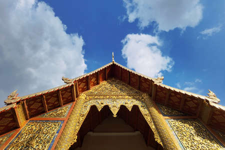 The beautiful thai temple roof of a buddhist temple in thailand under blue skyの写真素材