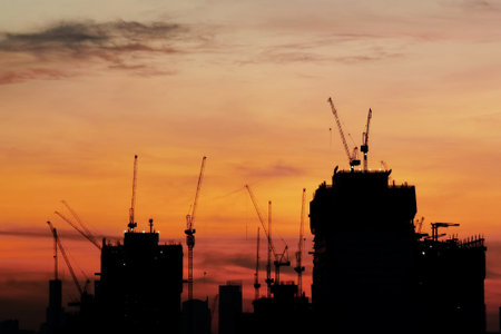 Silhouette building crane and buildings under construction against evening sky.の写真素材