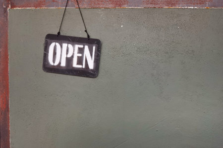 Board with lettering open hanging on wooden wallの写真素材