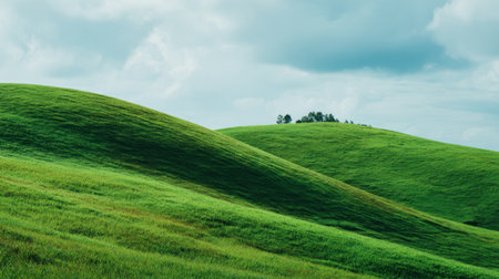 Experience the serene beauty of lush green hills under a dramatic sky filled with soft clouds, creating a picturesque natural landscape.の素材