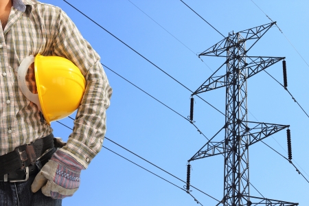 Electrician and high voltage power pylon against blue skyの写真素材