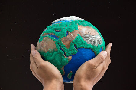 man holding globe made from clay on his hands  with dark sky and star backgroundの写真素材