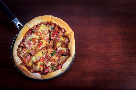 delicious pizza in pan on wooden backgroundの写真素材