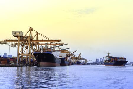 Container cargo freight ship with crane bridge in shipyard at twilight for logistic Import an...