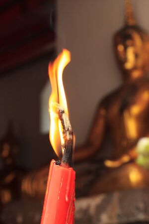 A single burning red candle at Wat Pho in bangkok, thailand の写真素材