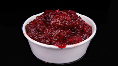 Vibrant cranberry sauce pops on sleek black background, Ai Generated.の素材