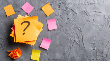 Orange sticky notes with a question mark stand out against soft pastels, illustrating the theme of confusion on a textured surface.の素材