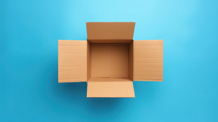 A top view of a solitary cardboard box offers a contrast of warm brown against a cool blue background.の素材