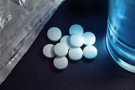 white pills placed near the glass of water on the bedside table, insomnia.の写真素材