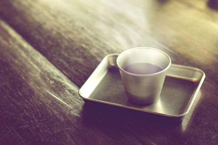 black coffee is served hot in stainless steel cup on wood table in cafe.の写真素材