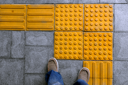 shoes on block tactile paving for blind handicap on tiles pathway, walkway for blindness people.の写真素材