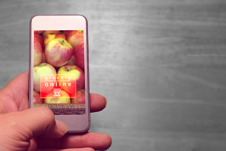 hand holding mobile with grocery online text on wood background